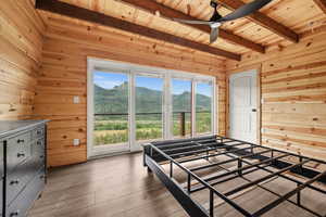 Bedroom featuring wood walls, wood ceiling, beam ceiling, a mountain view, and wood-type flooring