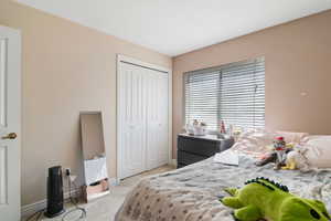 Bedroom with light colored carpet, baseboards, and a closet