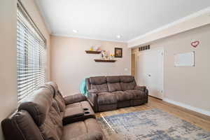 Living room featuring wood finished floors, baseboards, ornamental molding, and recessed lighting