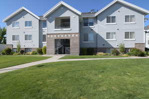 Multi unit property with a front yard, brick siding, and a balcony