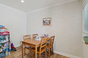 Dining space with light wood-style flooring, crown molding, baseboards, and recessed lighting