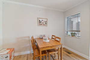 Dining space with wood finished floors, ornamental molding, and baseboards