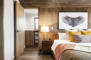 Bedroom featuring wood-type flooring, wooden walls, and baseboards