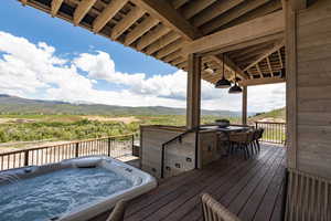 Wooden terrace featuring a mountain view, an outdoor hot tub, and outdoor dining area