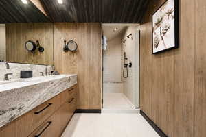 Bathroom with a tile shower, vanity, wood ceiling, and tile patterned flooring