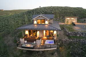 Back of house with a forest view, a standing seam roof, metal roof, and an outdoor living space with a fire pit