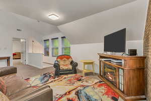 Carpeted living room with baseboards, visible vents, and vaulted ceiling
