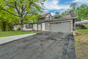 Tudor home featuring a garage, board and batten siding, a front yard, brick siding, and driveway