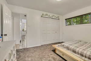Bedroom with baseboards, a closet, and light colored carpet