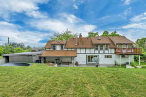 Rear view of house with a yard, a shingled roof, a patio, and a chimney