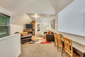 Living area with carpet, lofted ceiling, and a brick fireplace