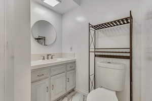 Bathroom featuring toilet, baseboards, marble finish floor, and vanity