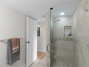 Full bathroom featuring a shower stall, tile patterned floors, and baseboards