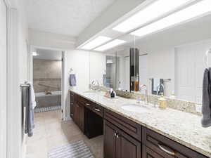 Bathroom with tile patterned flooring, double vanity, tiled bath, and a shower