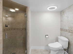 Bathroom with tile patterned floors, toilet, and a shower stall