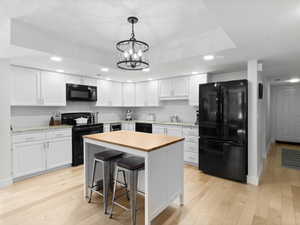 Kitchen featuring black appliances, light countertops, white cabinetry, recessed lighting, and light wood-style floors