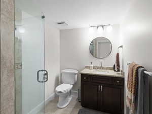 Bathroom featuring tile patterned floors, a shower stall, toilet, vanity, and baseboards