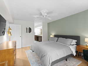 Master Bedroom with light wood-style floors, ceiling fan, ensuite bath, and baseboards