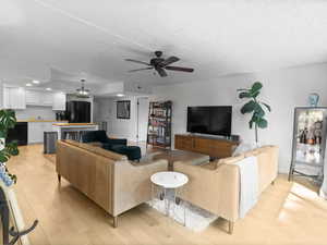 Living room with light wood finished floors, a ceiling fan, and recessed lighting