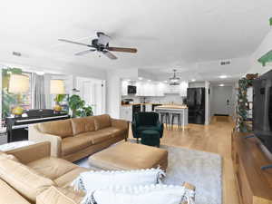 Living area with a ceiling fan, light wood-type flooring, and recessed lighting