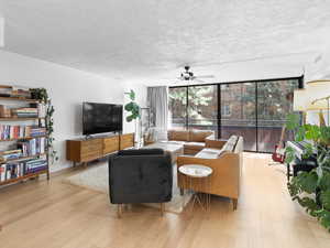 Living room featuring a wall of windows, ceiling fan, and wood finished floors