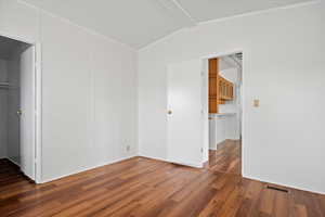 Empty room with wood finished floors and lofted ceiling