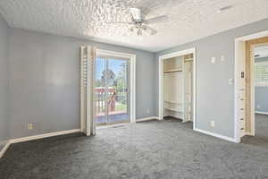 Unfurnished bedroom with access to outside, a textured ceiling, carpet flooring, baseboards, and a ceiling fan