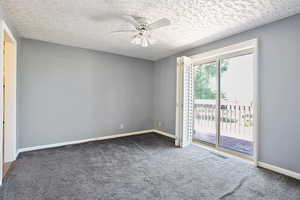 Empty room with a ceiling fan, dark carpet, a textured ceiling, and baseboards