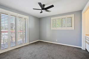 Unfurnished room with plenty of natural light, carpet floors, ceiling fan, and baseboards