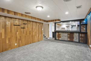Indoor dry bar with carpet floors, wooden walls, and stairs