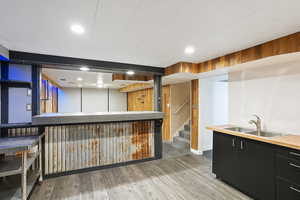 Indoor bar featuring wood finished floors, recessed lighting, baseboards, and stairway
