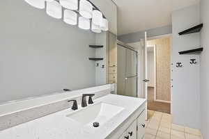 Full bathroom featuring tile patterned flooring, a tile shower, and vanity