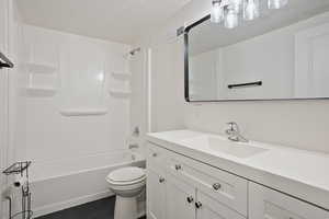 Bathroom featuring toilet, tile patterned flooring, a textured ceiling, vanity, and washtub / shower combination