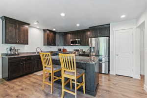 Kitchen featuring appliances with stainless steel finishes, light wood finished floors, a kitchen breakfast bar, a center island, and recessed lighting