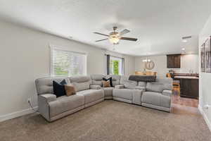 Carpeted living area featuring a chandelier, a ceiling fan, baseboards, a sink, and recessed lighting