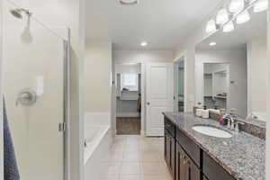 Bathroom featuring a stall shower, tile patterned flooring, a bath, vanity, and a walk in closet