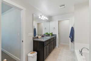 Bathroom featuring vanity, a tub to relax in, baseboards, and tile patterned floors