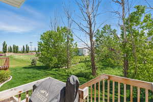 View of green lawn featuring a wooden deck