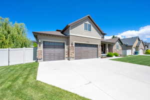 View of front facade featuring stone siding, driveway, stucco siding, and an attached garage