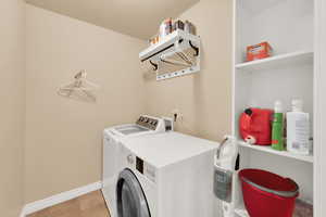Washroom featuring washing machine and clothes dryer and baseboards