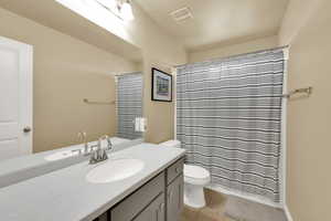 Full bathroom with toilet, vanity, tile patterned floors, and curtained shower