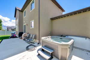 View of patio with a hot tub and fence