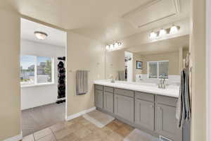 Full bath with double vanity, baseboards, tile patterned flooring, and a walk in closet