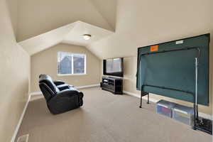 Sitting room featuring vaulted ceiling, carpet, and baseboards