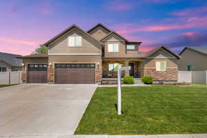 View of front of house with stone siding, stucco siding, concrete driveway, and a garage