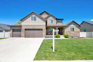 View of front of property with stone siding, stucco siding, concrete driveway, and a garage