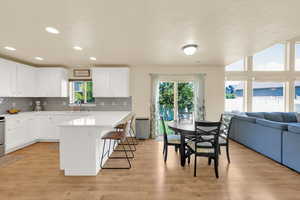 Kitchen featuring a sink, a breakfast bar area, light wood-style floors, light countertops, and backsplash