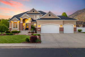 View of front facade featuring driveway, stucco siding, an attached garage, and brick siding