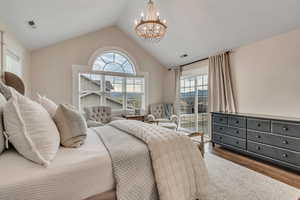Bedroom featuring a chandelier, wood finished floors, access to outside, and vaulted ceiling