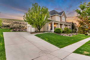 View of front facade featuring covered porch, a front yard, and driveway